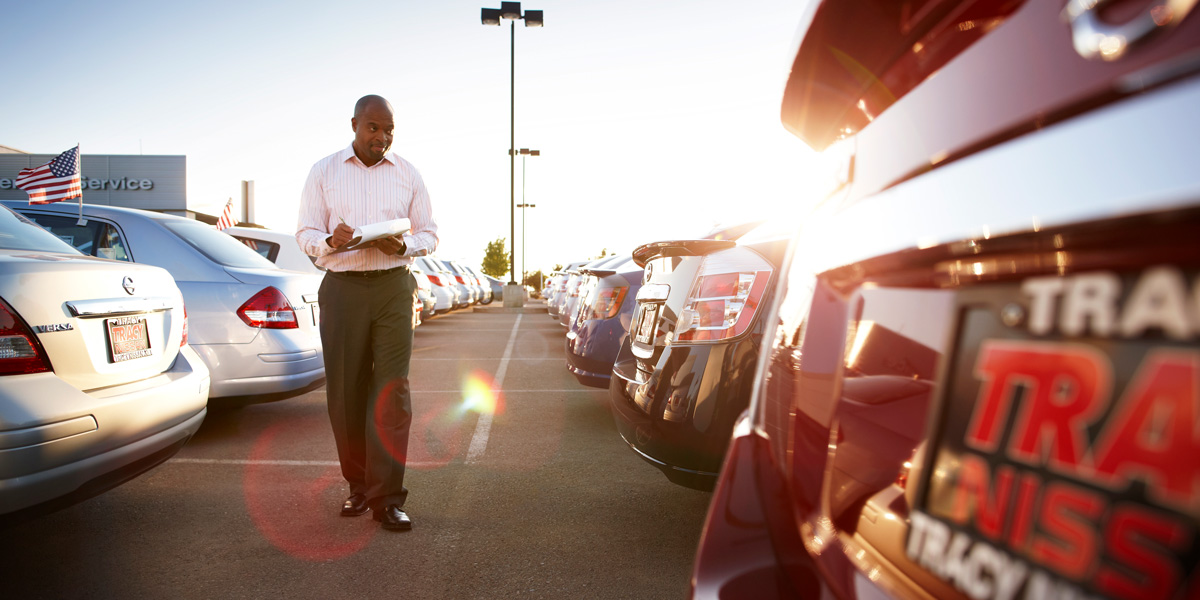 Car dealer looking at the rear of cars