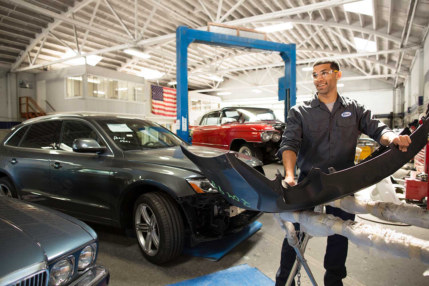 Man holds a car part in a garage