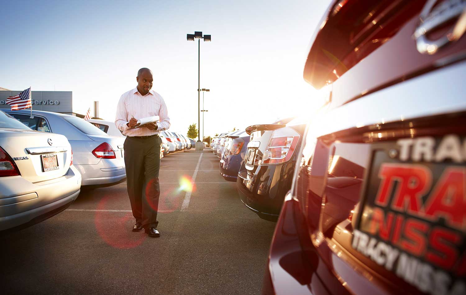 Car dealer walks through dealership parking lot