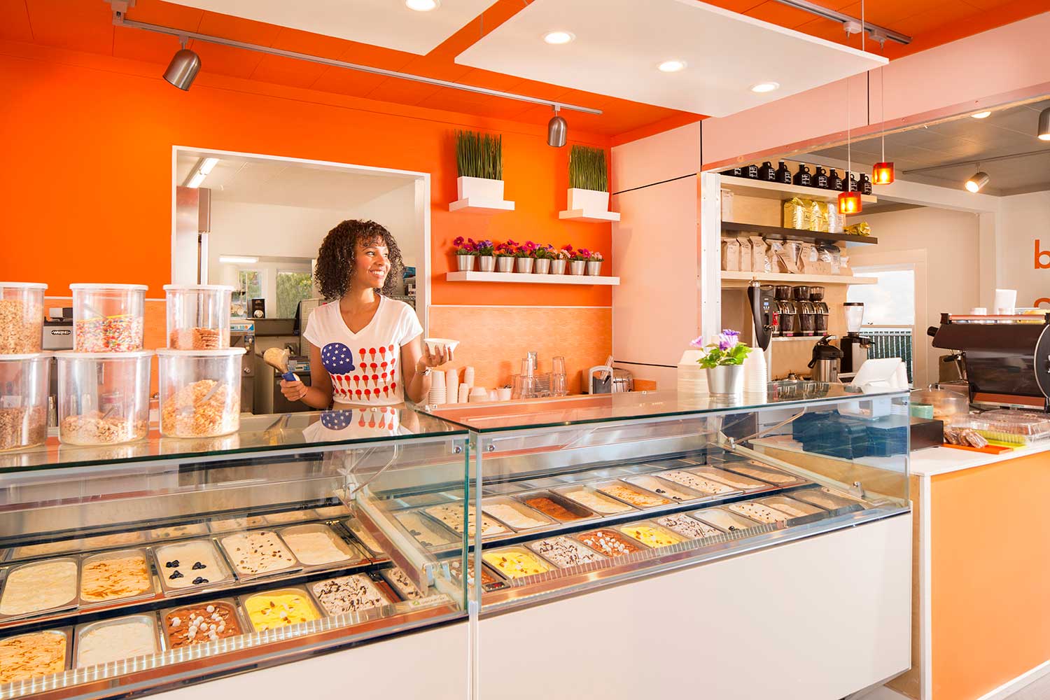 Woman scoops ice cream behind counter