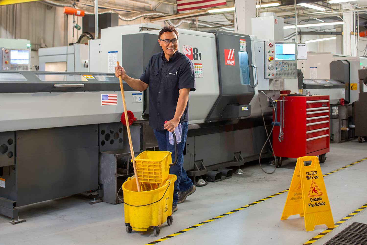 Man mops floor of manufacturing warehouse