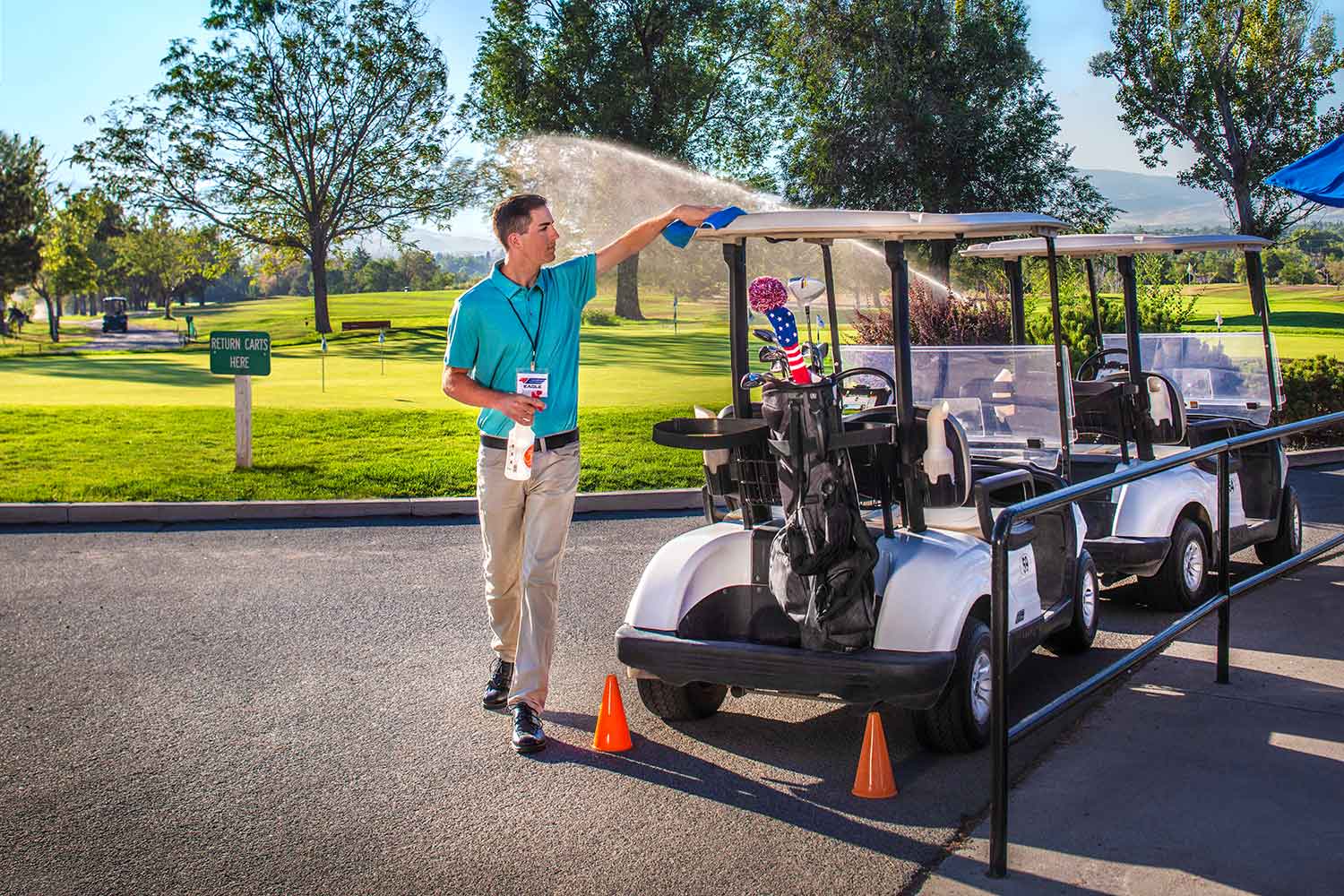 Man cleans gold carts near a golf course