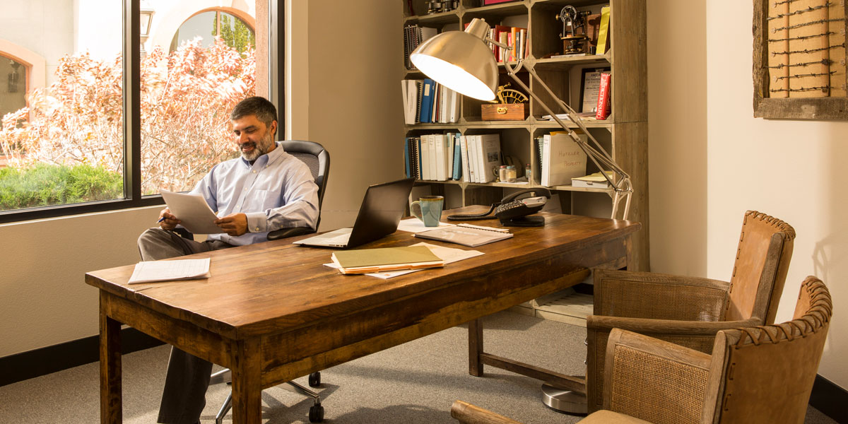 Man at desk reading from a piece of paper