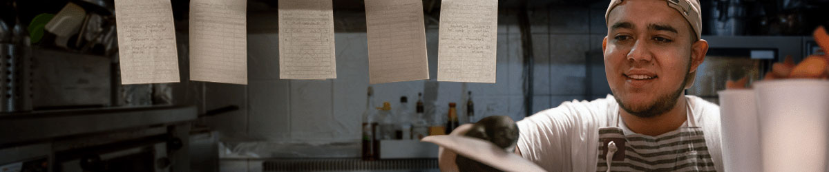 Man works in a kitchen as he cooks and takes orders