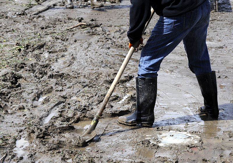 Workers cleaning up mud after a natural disaster