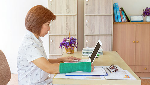 Woman with arm injury working at computer