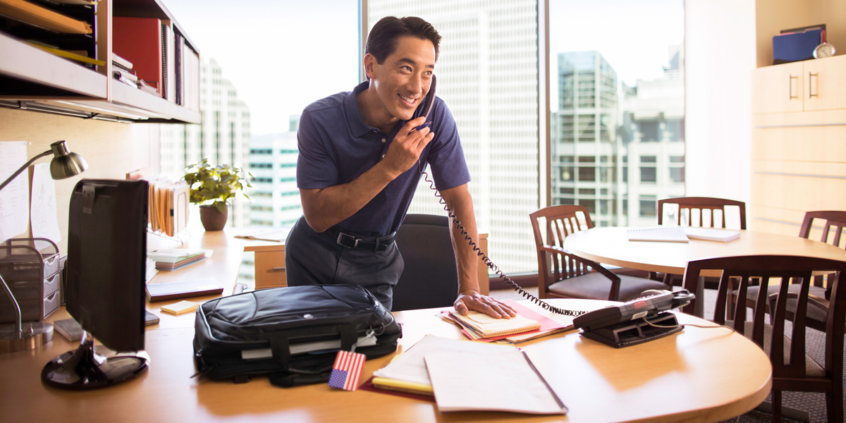 Man on the phone while standing above his desk